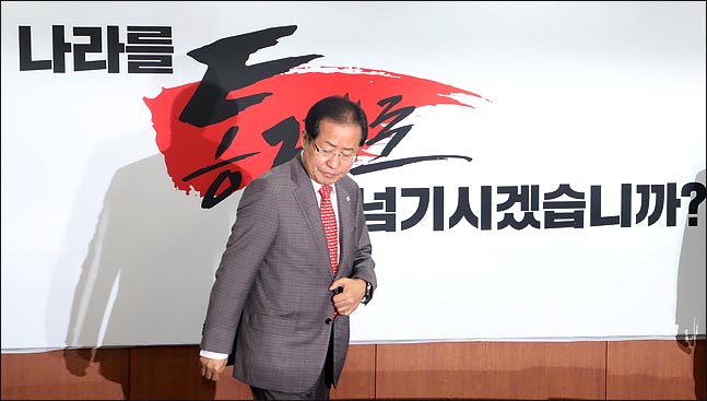 홍준표 자유한국당 대표가 4월 25일 오전 서울 여의도 당사에서 지방선거 필승 슬로건 ‘나라를 통째로 넘기시겠습니까’를 공개한 뒤 자리에 앉고 있다. ⓒ데일리안 박항구 기자