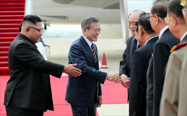 문재인 대통령이 18일 오전 평양 순안공항에 도착해 김정은 북한 국무위원장이 지켜보는 가운데 북측 고위급 인사들과 악수하고 있다. ⓒ평양사진공동취재단